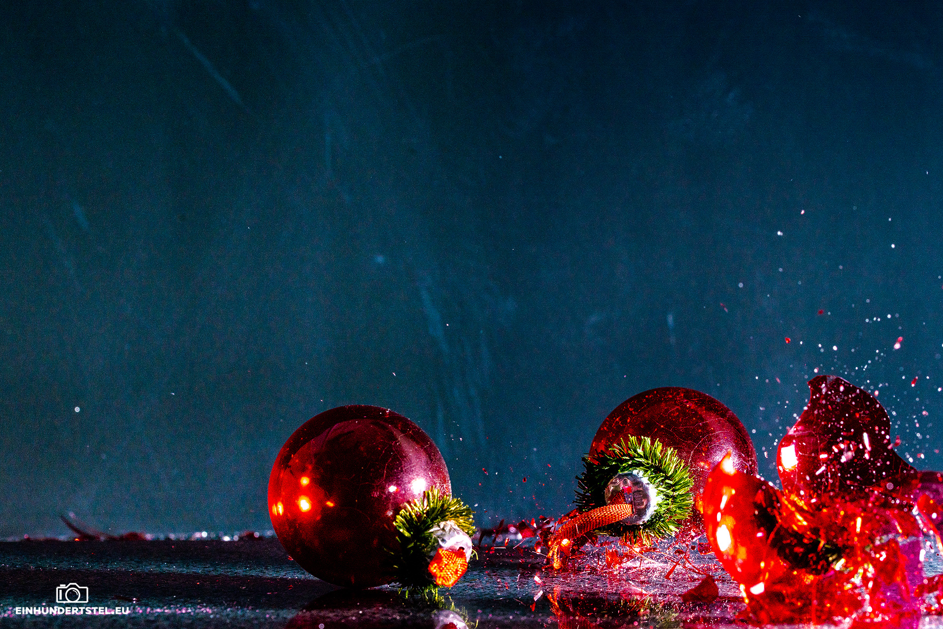 Mit Pulver gefüllte Weihnachtskugeln zerplatzen auf dem Boden. Splitter fliegen durch die Luft.